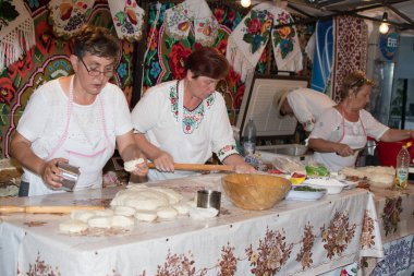 Bükreş, Romanya, 1 Eylül 2019: Geleneksel kıyafet giymiş bir adam ekmek hazırlıyor. Ahşap taş fırınında taze pişmiş ekmek.