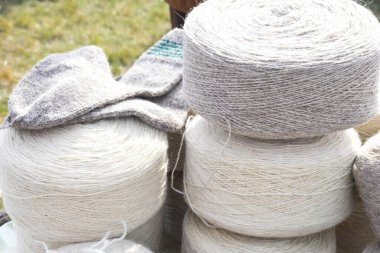 Yünlü çorap yapımında kullanılan koca doğal yün rulo tekerlekleri. Pazar yerinde ya da dükkanda tezgahın üstünde, panayır sırasında satılık yün. Beyaz ve gri lif dokusu