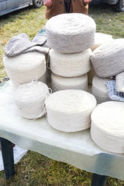 Yünlü çorap yapımında kullanılan koca doğal yün rulo tekerlekleri. Pazar yerinde ya da dükkanda tezgahın üstünde, panayır sırasında satılık yün. Beyaz ve gri lif dokusu