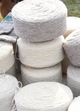 Yünlü çorap yapımında kullanılan koca doğal yün rulo tekerlekleri. Pazar yerinde ya da dükkanda tezgahın üstünde, panayır sırasında satılık yün. Beyaz ve gri lif dokusu
