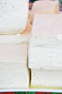Süpermarketteki şarküteride satılık bitkilerle tatlandırılmış çeşitli peynir tekerleri. Yemek festivalinde Romanya 'nın geleneksel yumuşak ve sert peynir çeşitleri tezgahın üzerinde
