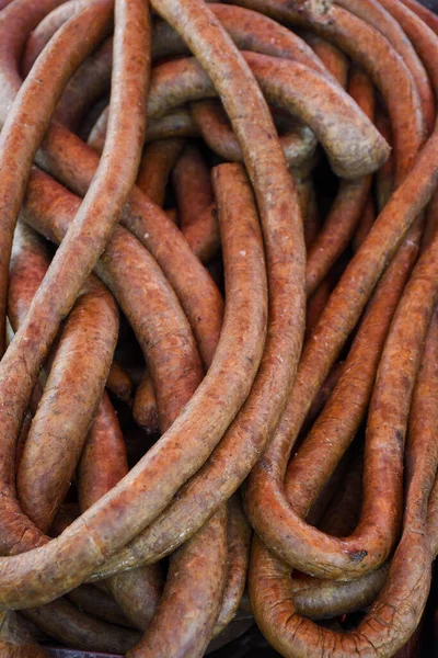 Assorted meat products, sausages, chorizo, spices on a dark table. View from above. Large selection of different dried spicy seasoned beef and pork sausages. Street food, fast food assortment of meat