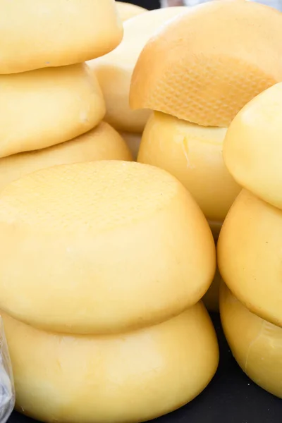 A variety of wheels of cheese seasoned with herbs for sale at the deli counter in the supermarket. Romanian traditional assortment of soft and hard cheeses on the counter top during food festival