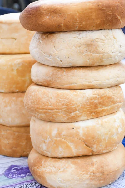 A variety of wheels of cheese seasoned with herbs for sale at the deli counter in the supermarket. Romanian traditional assortment of soft and hard cheeses on the counter top during food festival