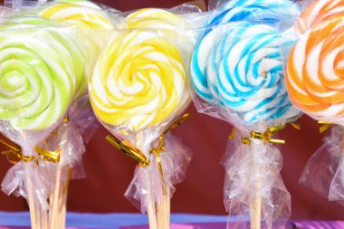 Satılık çok renkli spiral lolipop sergisi. Noel çocuklar için ödül konseptidir. Mutlu sarı, yeşil, mavi, turuncu girdap şekeri