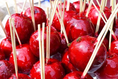 Çiftçi pazarında ya da kasaba fuarında satılmak üzere çubuklarda satılan tatlı, kırmızı şekerli elma şekerlemeleri. Şükran Günü ve Cadılar Bayramı ev yapımı kırmızı karamel jöleli elma şekerlemesi.