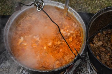 Kamp ateşi sırasında yemek pişiren çok büyük bir kazan, yemek festivali sırasında hazırlanan büyük kaplar. Ateşin üzerinde asılı duran bir turist potası. Ateşin üstünde tencerede yemek pişirmek. Kamp kavramı