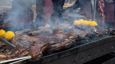 Şefin elleri ızgarada çok büyük bir parça et pişiriyor. Şef yaz yemeği festivali sırasında dışarıda barbekü konseptinde et pişiriyor. Mangal partisi, misafirler için yemek pişirme ve yemek hazırlama. Çeşit