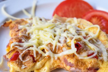 Geleneksel köylü omleti jambon, peynir, domates, kırmızı biber, izole edilmiş domuz pastırması ve beyaz bir tabakta servis edilir.