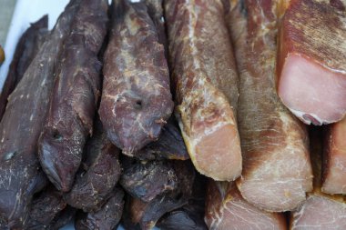 Çeşitli et ürünleri, sosisler, sucuk, karanlık bir masada baharatlar. Yukarıdan bak. Farklı baharatlı baharatlı sığır eti ve domuz sosisi çeşitleri. Sokak yemekleri, fast food çeşitleri.