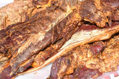 Çeşitli et ürünleri, sosisler, sucuk, karanlık bir masada baharatlar. Yukarıdan bak. Farklı baharatlı baharatlı sığır eti ve domuz sosisi çeşitleri. Sokak yemekleri, fast food çeşitleri.