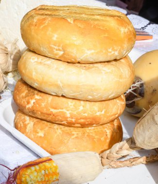 Süpermarketteki şarküteride satılık bitkilerle tatlandırılmış çeşitli peynir tekerleri. Yemek festivalinde Romanya 'nın geleneksel yumuşak ve sert peynir çeşitleri tezgahın üzerinde