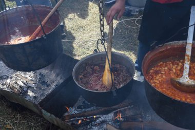 Kamp ateşi sırasında yemek pişiren çok büyük bir kazan, yemek festivali sırasında hazırlanan büyük kaplar. Ateşin üzerinde asılı duran bir turist potası. Ateşin üstünde tencerede yemek pişirmek. Kamp kavramı