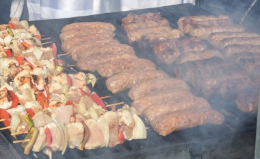 Şef piknik ya da yemek etkinliği sırasında et pişiriyor. Etlerin karışımı: sosis, domuz eti, tavuk, kuzu, koyun, sardalya, kızarmış veya ızgara, sağlıksız protein konsepti. Yağlı yiyecekler, kanserli yiyecekler