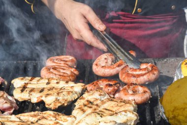 Şef piknik ya da yemek etkinliği sırasında et pişiriyor. Etlerin karışımı: sosis, domuz eti, tavuk, kuzu, koyun, sardalya, kızarmış veya ızgara, sağlıksız protein konsepti. Yağlı yiyecekler, kanserli yiyecekler