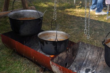 Kamp ateşi sırasında yemek pişiren çok büyük bir kazan, yemek festivali sırasında hazırlanan büyük kaplar. Ateşin üzerinde asılı duran bir turist potası. Ateşin üstünde tencerede yemek pişirmek. Kamp kavramı