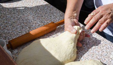 Kadın eli hamuru oklavayla yuvarlıyor, turta ya da pizza yapıyor, ev yapımı.