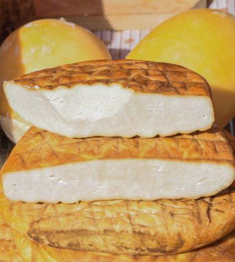 Süpermarketteki şarküteride satılık bitkilerle tatlandırılmış çeşitli peynir tekerleri. Yemek festivalinde Romanya 'nın geleneksel yumuşak ve sert peynir çeşitleri tezgahın üzerinde