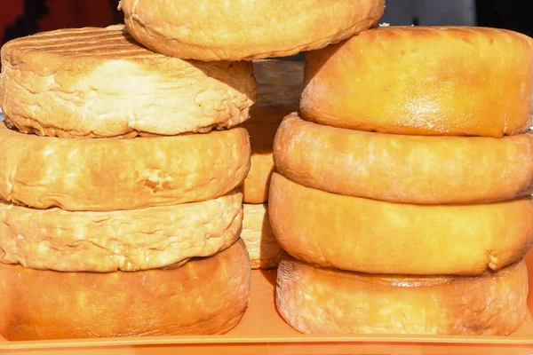 A variety of wheels of cheese seasoned with herbs for sale at the deli counter in the supermarket. Romanian traditional assortment of soft and hard cheeses on the counter top during food festival