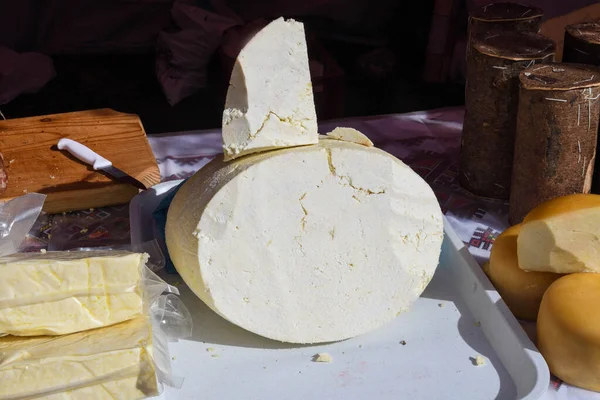 A variety of wheels of cheese seasoned with herbs for sale at the deli counter in the supermarket. Romanian traditional assortment of soft and hard cheeses on the counter top during food festival