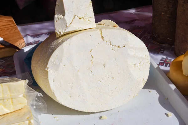 スーパーのデリカウンターでは ハーブで味付けされたチーズのホイールが販売されています 食の祭典の間にカウンターの上に柔らかくて硬いチーズのルーマニアの伝統的な品揃え — ストック写真