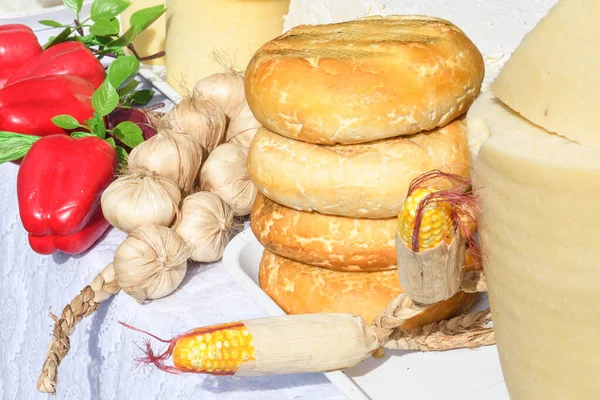A variety of wheels of cheese seasoned with herbs for sale at the deli counter in the supermarket. Romanian traditional assortment of soft and hard cheeses on the counter top during food festival