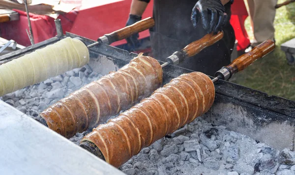 Kurtos kalacs or chimney cakes, preparing cooking on charcoal grill, street food traditional Hungarian, during food festival. Kurtos Kalacs traditional hungarian cake, baked with sugar, honey and nuts