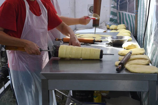 Kurtos kalacs or chimney cakes, preparing cooking on charcoal grill, street food traditional Hungarian, during food festival. Kurtos Kalacs traditional hungarian cake, baked with sugar, honey and nuts