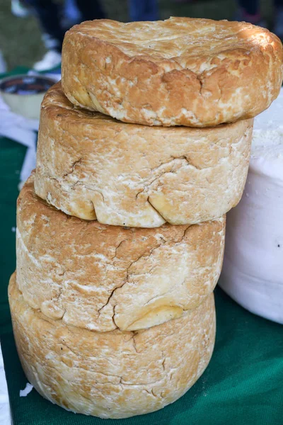 A variety of wheels of cheese seasoned with herbs for sale at the deli counter in the supermarket. Romanian traditional assortment of soft and hard cheeses on the counter top during food festival