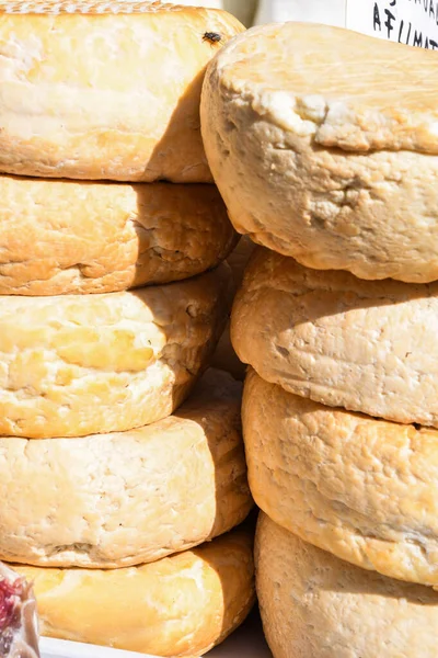 A variety of wheels of cheese seasoned with herbs for sale at the deli counter in the supermarket. Romanian traditional assortment of soft and hard cheeses on the counter top during food festival