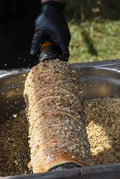 Kurtos kalacs or chimney cakes, preparing cooking on charcoal grill, street food traditional Hungarian, during food festival. Kurtos Kalacs traditional hungarian cake, baked with sugar, honey and nuts