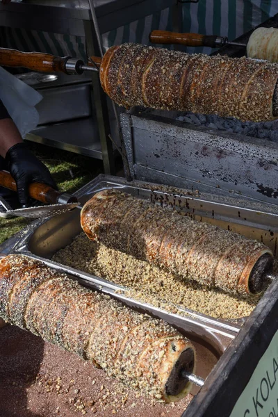 Kurtos kalacs or chimney cakes, preparing cooking on charcoal grill, street food traditional Hungarian, during food festival. Kurtos Kalacs traditional hungarian cake, baked with sugar, honey and nuts