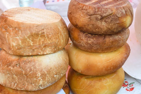 A variety of wheels of cheese seasoned with herbs for sale at the deli counter in the supermarket. Romanian traditional assortment of soft and hard cheeses on the counter top during food festival