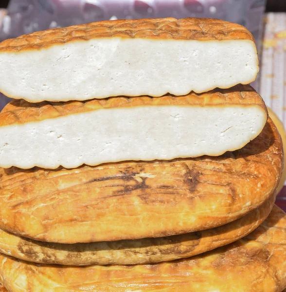 A variety of wheels of cheese seasoned with herbs for sale at the deli counter in the supermarket. Romanian traditional assortment of soft and hard cheeses on the counter top during food festival