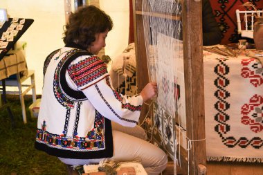 Bran, Romanya, 29 Eylül 2019: Geleneksel Romanya halısını dokuma tezgahında ören kadın