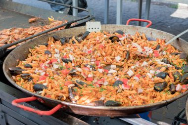 Otel brunch büfesi sırasında havuzun yanındaki bahçede büyük tavada pişen taze deniz mahsullü makarna. Taze Yemek Büfesi Yemek Yemeği Paylaşım Partisi Konsepti