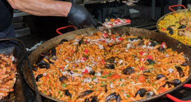 Otel brunch büfesi sırasında havuzun yanındaki bahçede büyük tavada pişen taze deniz mahsullü makarna. Taze Yemek Büfesi Yemek Yemeği Paylaşım Partisi Konsepti