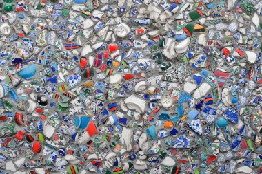 Kırık seramik çömlek parçalarıyla dekore edilmiş bir duvar. Çok renkli doku ve arkaplan.