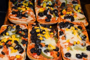 Zeytinli vejetaryen pizza dilimleri, mozzarella, tatlı mısır ve domates sosu, fast food sokak festivali sırasında satılık.