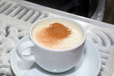 Beyaz sade sütlü, tarçın tozu ve saglikli baharat ve sonbahar yaprağını beyaz sade ahşap masaya yapıştıran Türkiye içeceği. Sahlep arkaplanı