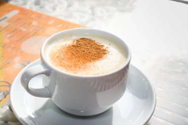 Beyaz sade sütlü, tarçın tozu ve saglikli baharat ve sonbahar yaprağını beyaz sade ahşap masaya yapıştıran Türkiye içeceği. Sahlep arkaplanı