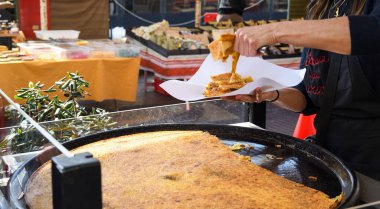 Nice, Fransa, 25 Şubat 2020: Büyük bir tabak Farinata ya da Cecina ya da Torta di ceci mayasız krep ya da Ceneviz kaynaklı nohut krepi ahşap fırında pişirilmiş, soka satılık.