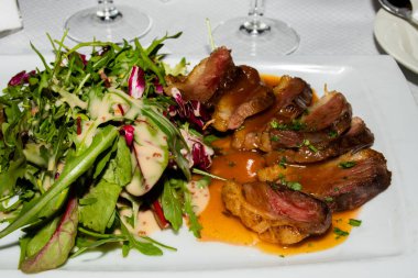 Geleneksel ördek filetosu, az pişmiş, Fransız restoranında salatayla servis ediliyor. Orijinal otantik tarif, üstüne portakal sosu sosu.