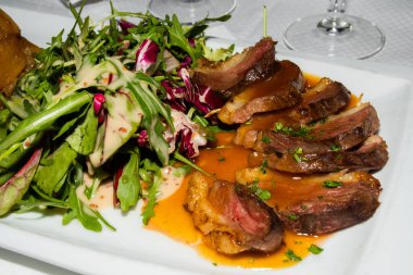 Geleneksel ördek filetosu, az pişmiş, Fransız restoranında salatayla servis ediliyor. Orijinal otantik tarif, üstüne portakal sosu sosu.