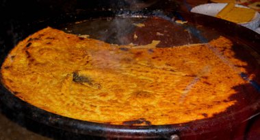 Big Plate of Farinata or Cecina or Torta di ceci thin unleavened pancake or crepe of chickpea flour originating in Genoa cooked in a wood oven, socca for sale clipart