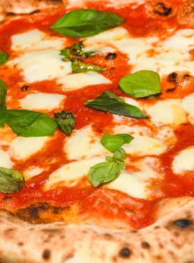 Pizza Margherita, San Marzano domatesleri, mozzarella peyniri, taze fesleğen, tuz ve ekstra bakire zeytinyağından yapılmış tipik bir Napoli pizzasıdır. Dilimlenmemiş bir parça, restoranda bir tabakta servis edilmiş.