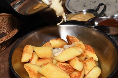 Tavada kızarmış patates köftesi, sosis, kızarmış soğan, peynir sosu. Restoran masası düzenlemek, yemek konseptini cilalamak.