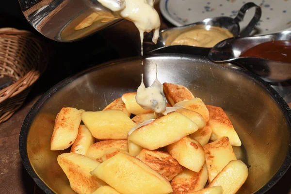 Fried potato dumplings served in a pan with sausages, fried onion, cheese sauce. Restaurant table setting, polish dinner concept