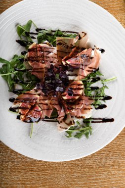 Geleneksel İtalyan salatası incirli jambonlu jambon ya da ince dilimlenmiş jambonlu jambonlu İtalyan salatası İtalyan restoranında beyaz tabakta servis edilir.