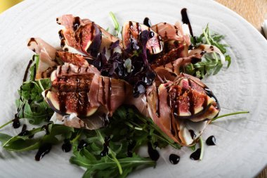 Geleneksel İtalyan salatası incirli jambonlu jambon ya da ince dilimlenmiş jambonlu jambonlu İtalyan salatası İtalyan restoranında beyaz tabakta servis edilir.